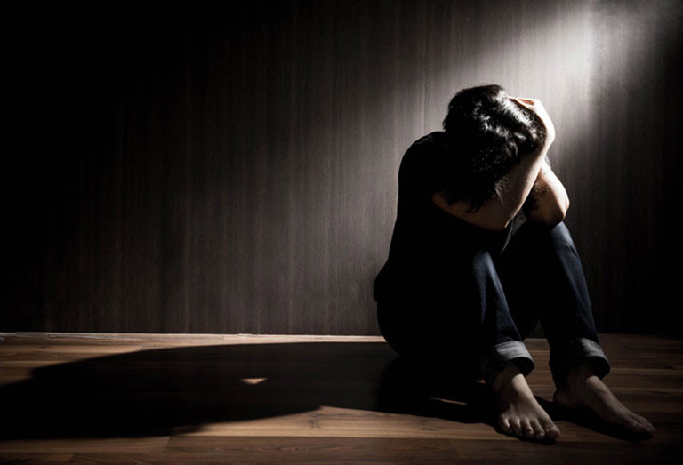 A child sitting alone on a couch in a dimly lit room, looking contemplative.